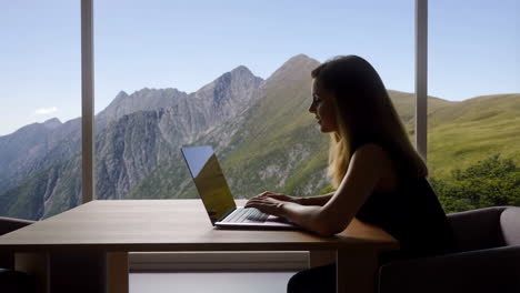 woman working on laptop with mountain view from window