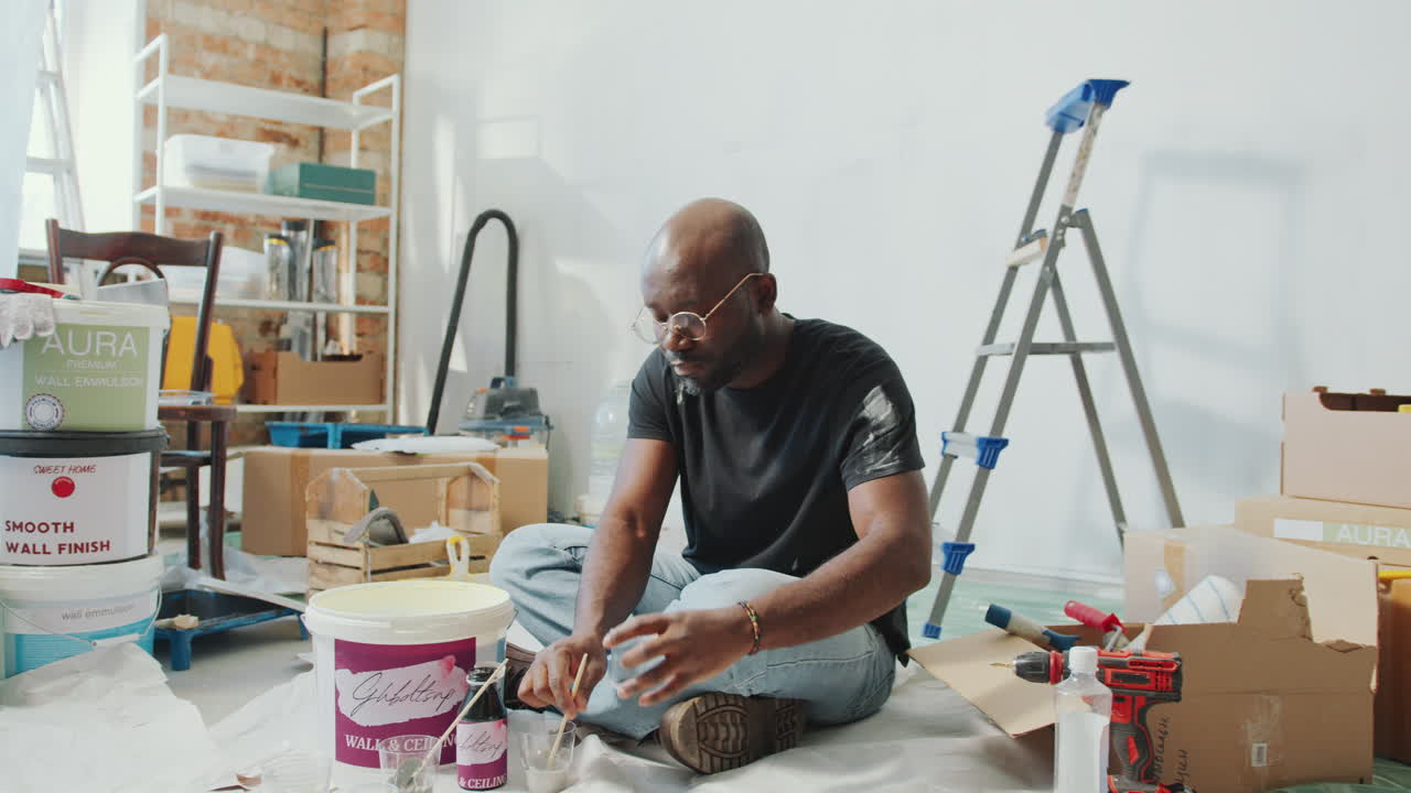 African American Man Mixing Paint Colors during Home Improvement