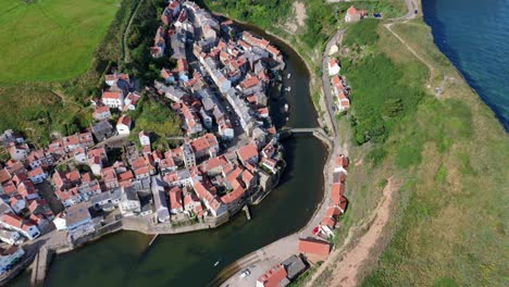 vista aérea de un dron del puerto de staithes en la costa del norte de yorkshire con el río, las casas, los barcos en una mañana soleada de agosto, verano