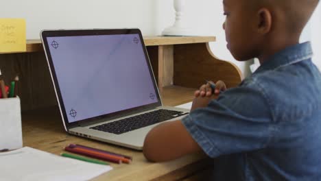 niño afroamericano en casa en clase escolar en línea, usando una computadora portátil con espacio de copia en la pantalla