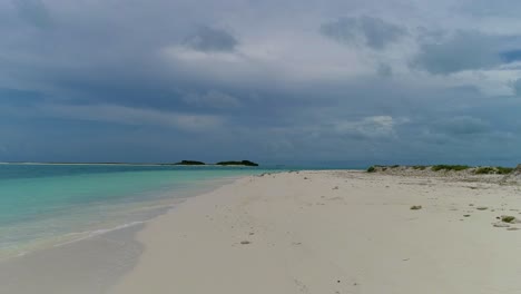 POV-walking-on-white-sand-shore-beach-with-sea-birds,-dolly-in-stunning-caribbean-island