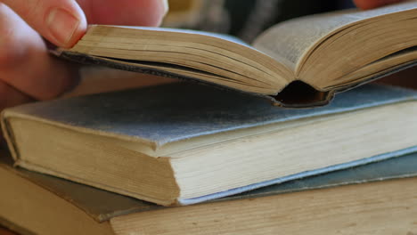 hands of a man holding and reading the holy scripture in the bible on a wooden table - close up