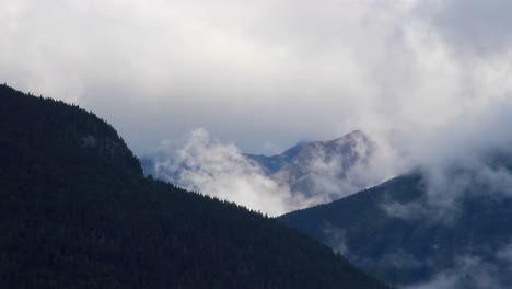 Niedrige-Wolken-Und-Nebel-Steigen-Auf,-Während-Die-Morgensonne-Die-Hohen-Berggipfel-Erwärmt