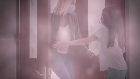 animation of light spots over caucasian woman and her daughter wearing face masks opening door