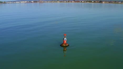 low angle orbit aerial view of navigation sea marker on calm blue sea