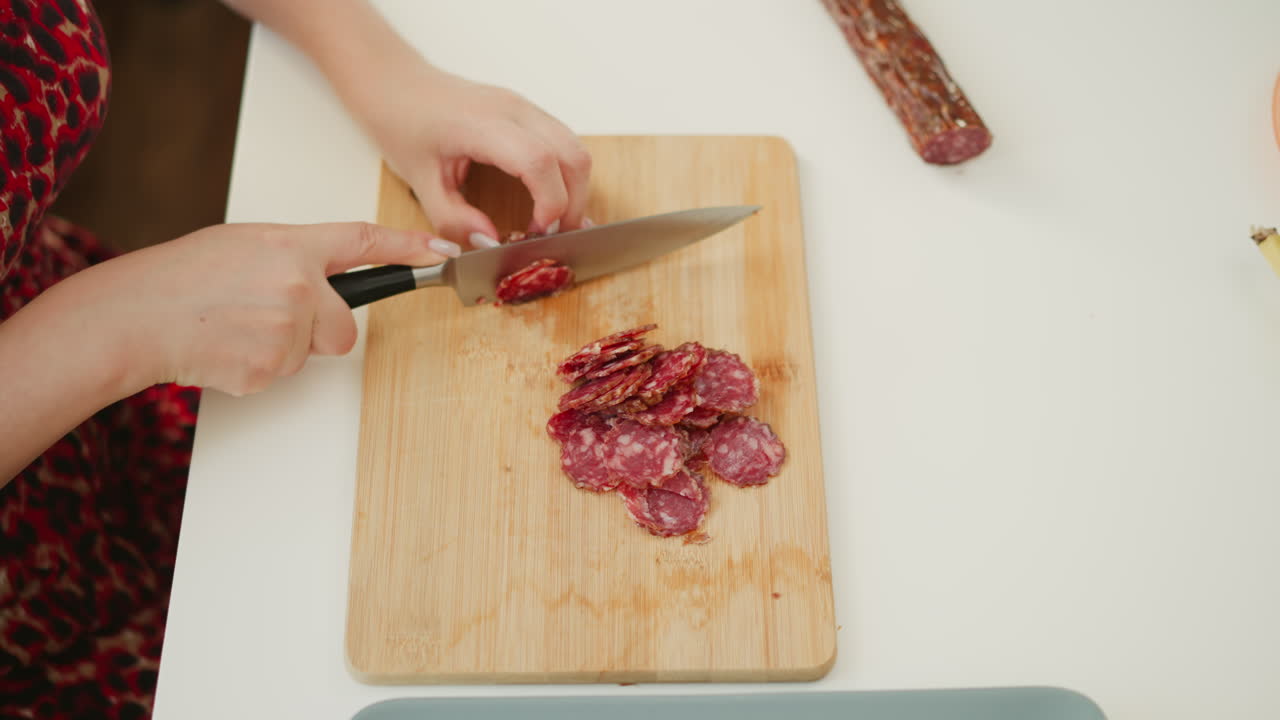 Woman cutting sausage on a wooden cutting board