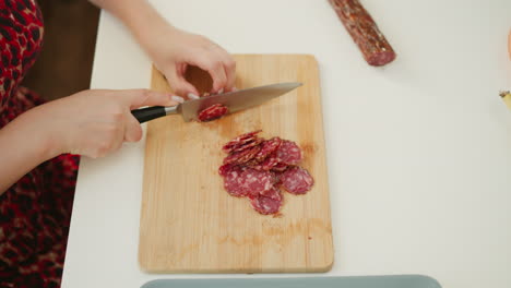 woman cutting sausage on a wooden cutting board