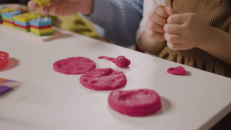 primer plano de dos alumnos en una escuela montessori jugando con formas apiladas y plastilina mientras el maestro los ayuda