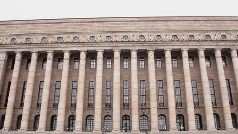 wide shot of the helsinki parliament house façade on a cloudy day, no people in view, imposing architecture, camera tilt up