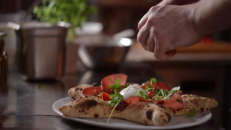 chef preparing a star-shaped pizza with burrata and prosciutto