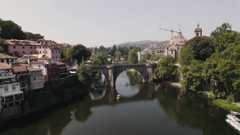 medieval bridge of amarante town with cityscape and river water, aerial flying forward view