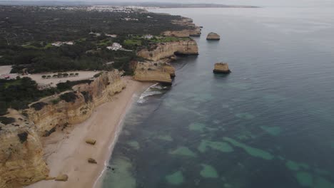 Aerial-view-flying-over-Benagil-caves,-Lagoa,-Algarve-Portugal-with-Atlantic-ocean-transparent-shoreline