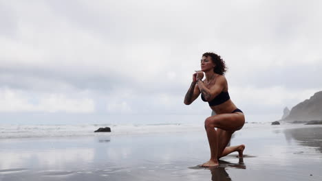 En-La-Playa,-Una-Mujer-Fitness-Estira-Las-Piernas-O-Realiza-Estocadas,-Mientras-Una-Atleta-Disfruta-De-Ejercicios-Relajantes-Frente-Al-Mar-En-Cámara-Lenta