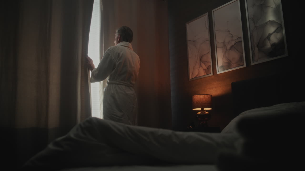A person in a robe stands in a bedroom