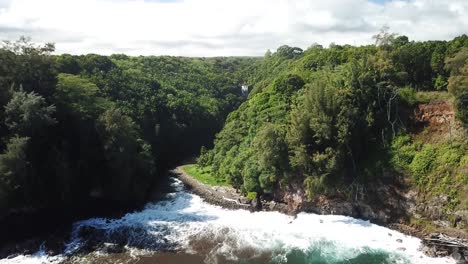 aerial view of lush tropical coastline with waterfall and ocean waves