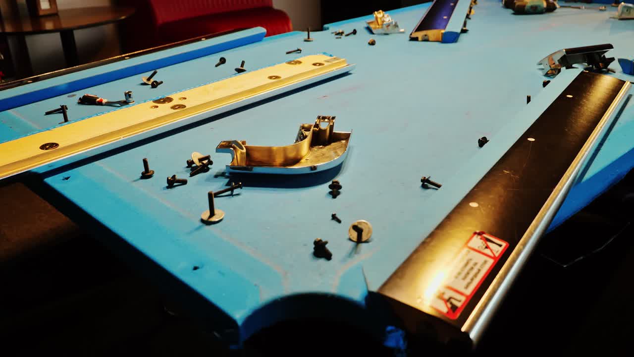 Billiard table in blue fabric during restoration, metal parts, screws scattered