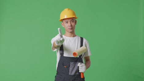 Asian Man Painter Wearing Safety Helmet Pointing At You And Disapproving With No Index Finger Sign While Standing In The Green Screen Background Studio