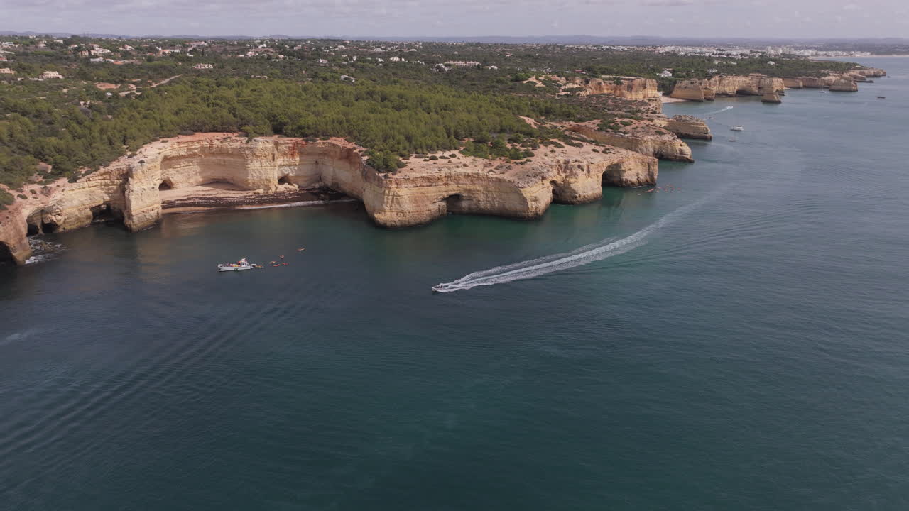 Aerial drone view of boat driving fast at the Benagil Sea Caves and Atlantic Ocean coastline in Benagil, Algarve, Portugal, Europe. Mediterranean natural landscape