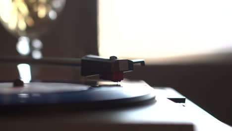 blue vinyl record playback on vintage gramophone with glass of white wine in background