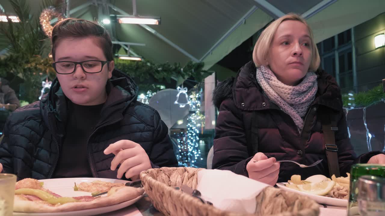 Mother and son eating in cafe, outside on the terrace, enjoying family meal together