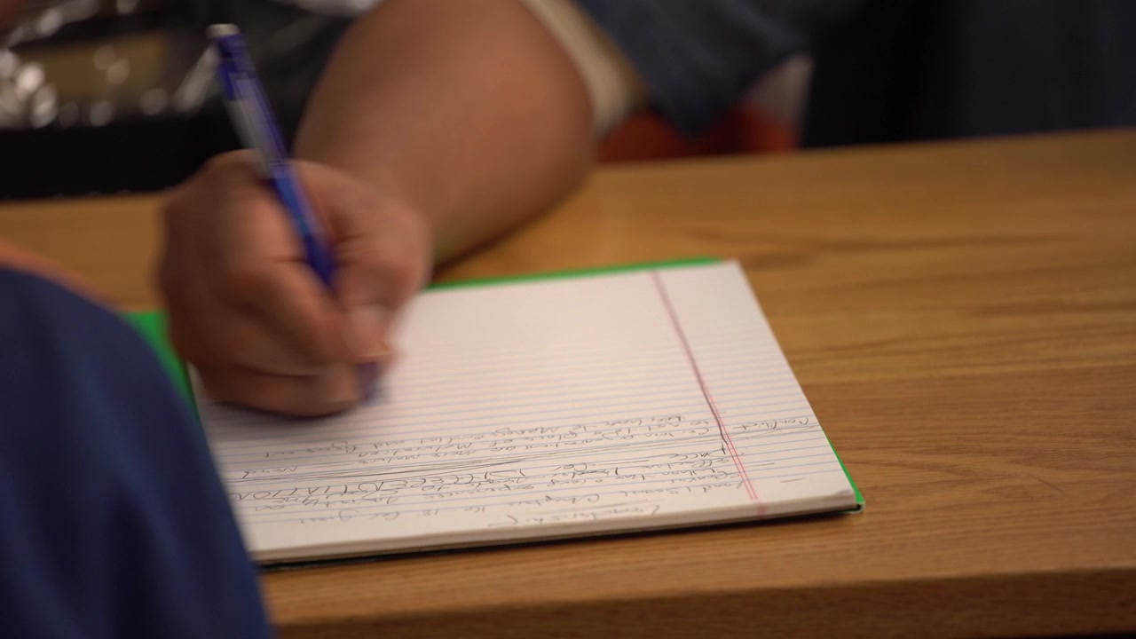 close up african american with papers writing hands in prison black inmate in jail education 4k classroom