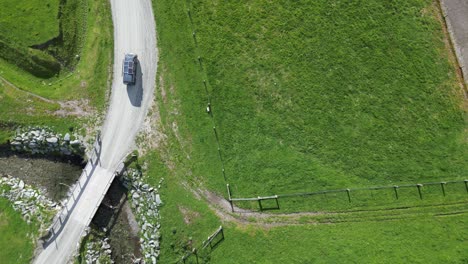 Navy-blue-van-driving-across-bridge-and-gravel-road