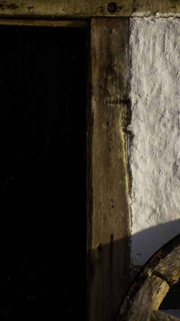 Una ruota di legno rustica accanto a una vecchia porta rivela il fascino del villaggio al tramonto