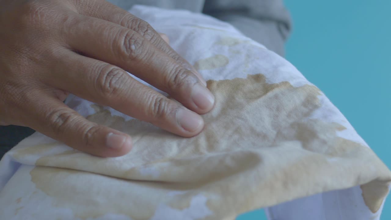 limpiando una mancha de café de una camisa blanca