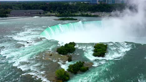 high drone orbit establishing of niagara falls showing massive curved drop and white mist rising upward