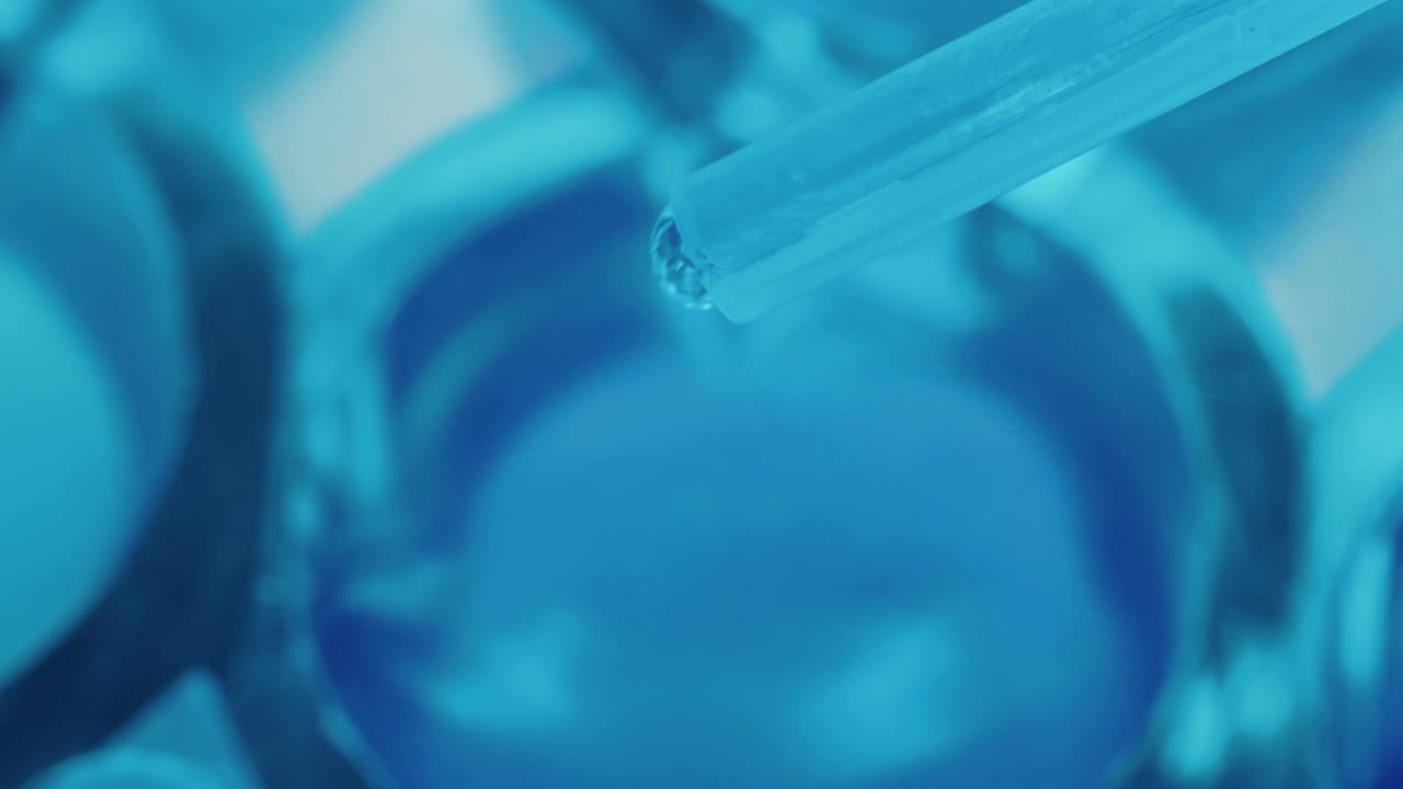 Liquid Dripping from Pipette into Microtiter Plate in Laboratory
