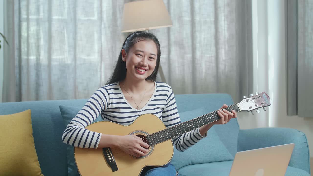 집에서 어쿠스틱 기타를 연주하는 젊은 여성