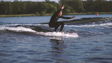 surfer on longboard surfing waves behind boat doing tricks