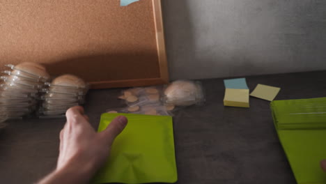 pov de persona empaquetando pastillas de pezón para el mercado, colocándolas en la mesa, agarrando la siguiente bolsa