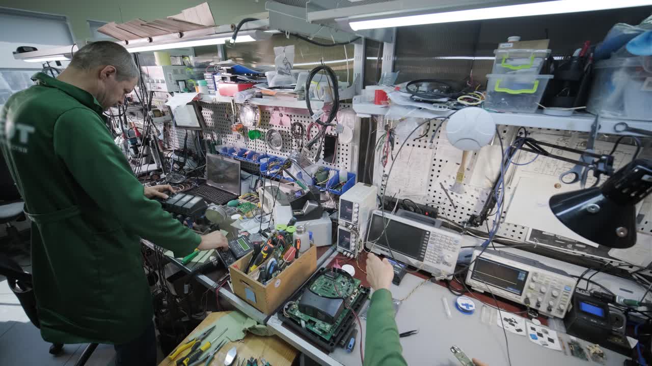 전자 장비 수리 공장 - 엔지니어 기술자가 현미경 아래 전자 장치의 인쇄 회로 보드를 용접합니다.