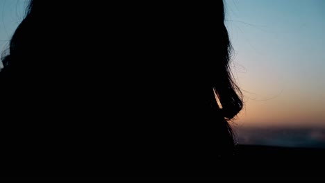 Cerrar-Silueta-De-Chica-Arreglando-El-Cabello-Por-La-Ventana-En-Una-Habitación-Oscura