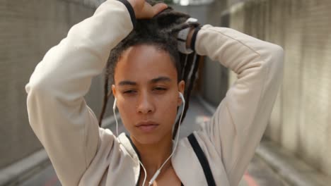 Front-view-of-young-African-American-woman-tying-her-updo-in-the-city-4k