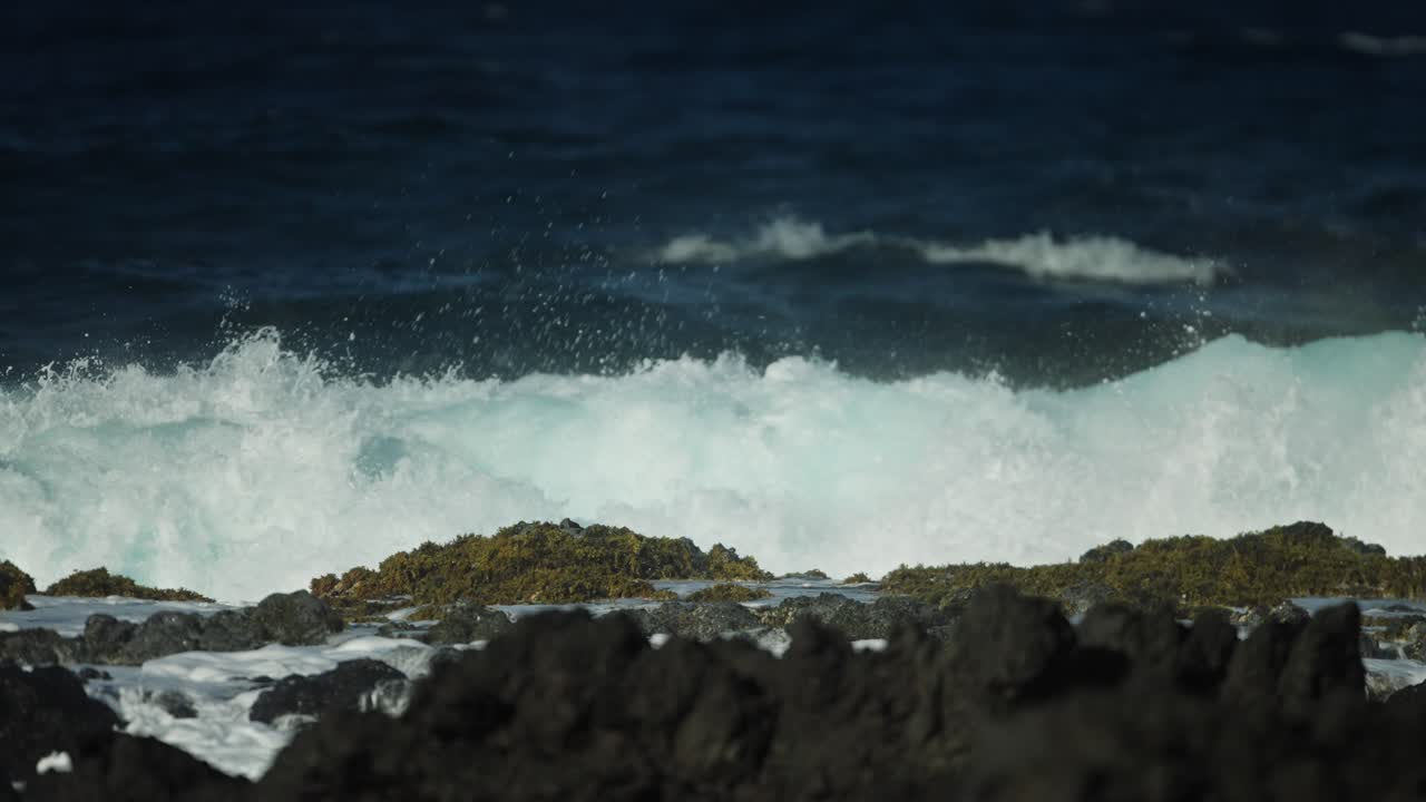 vista estática de movimiento lento frontal de fuertes olas oceánicas rodando a través del mar chocando y rociando a través de las rocas