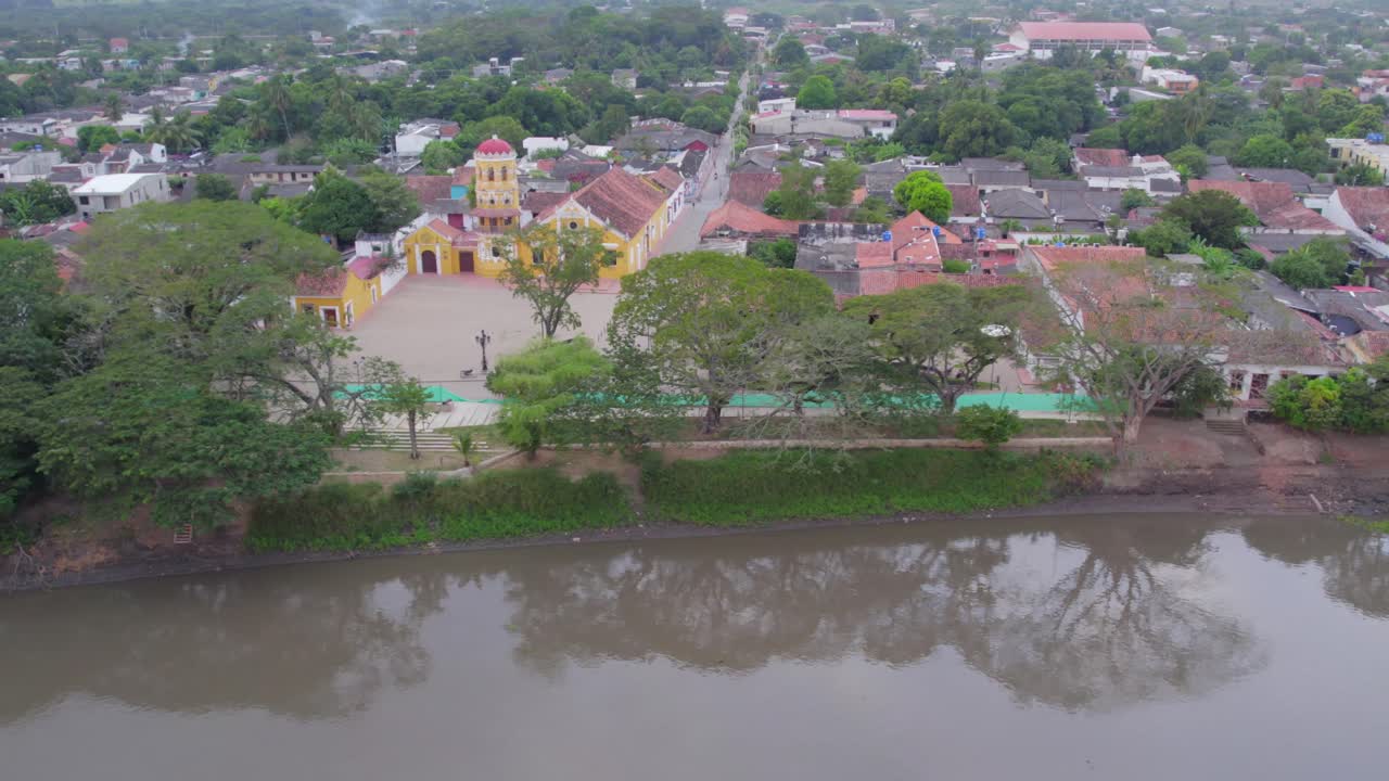 The drone rolls right over the serene waters of the Magdalena River, where lush trees cast perfect reflections on the glassy surface.