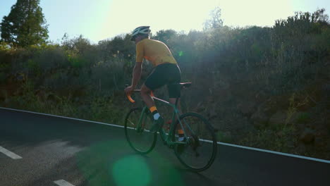 against the serene backdrop of the morning, a man cycles on a road bike for outdoor exercise along an unoccupied road. the slow-motion perspective intensifies the thrill of extreme sports