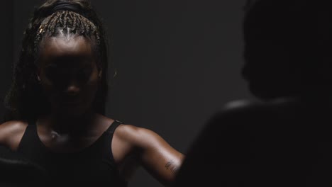 foto de estudio de una mujer poniéndose guantes de boxeo lista para pelear con un entrenador