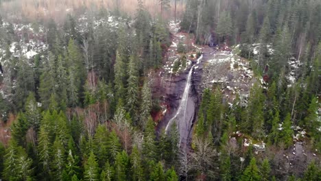 Aerial-view-of-a-waterfall-flowing-in-the-middle-of-a-forest-during-the-fall