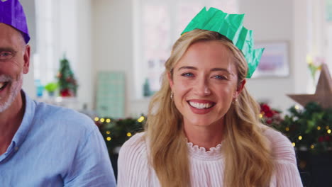 Portrait-Of-Multi-Generation-Family-Celebrating-Christmas-At-Home-Wearing-Paper-Hats-Before-Meal