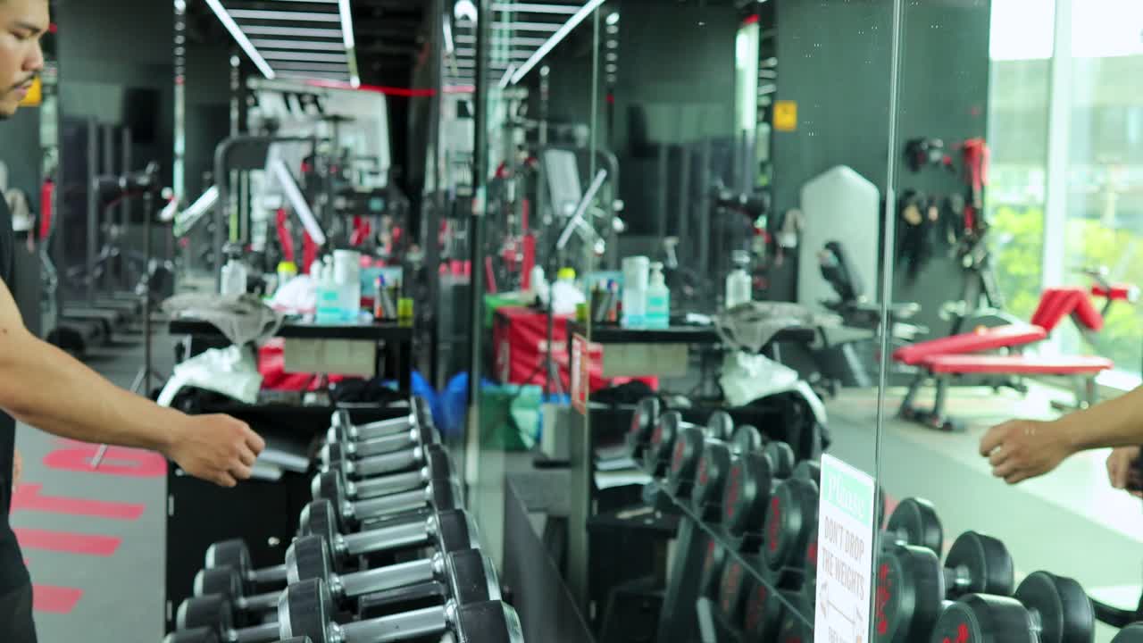 Trainer helps client choose dumbbells in modern gym, bright lighting, static camera, motivational atmosphere