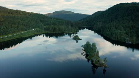 epic nature scene of calm norwegian lake surrounded by lush forest, aerial