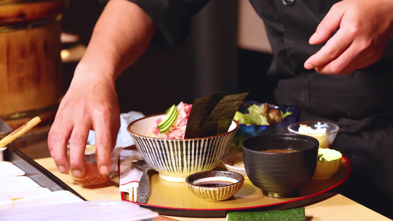 Um chef profissional serve uma bandeja de refeição japonesa tradicional com tigela de chirashi e sopa de missô