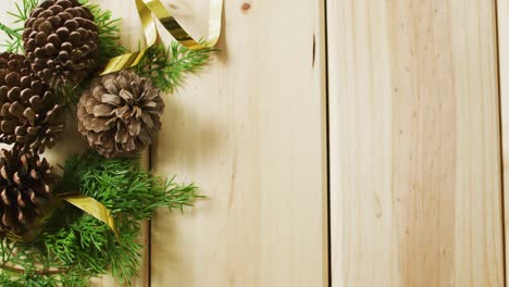 Video-of-christmas-decorations-with-pine-cones-and-copy-space-on-wooden-background