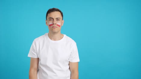 Man standing with polish flag painted on face smiling