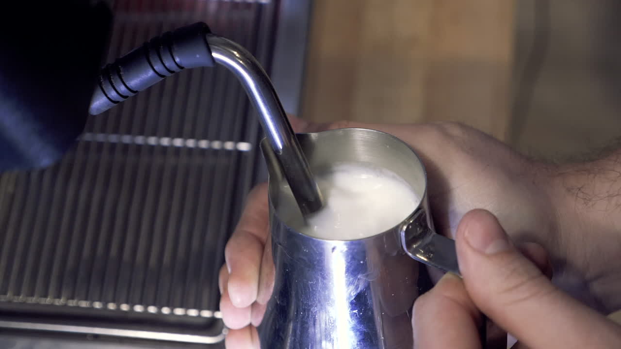 ラテやカプチーノのためのエスプレッソマシンを備えたバリスタの蒸しミルク