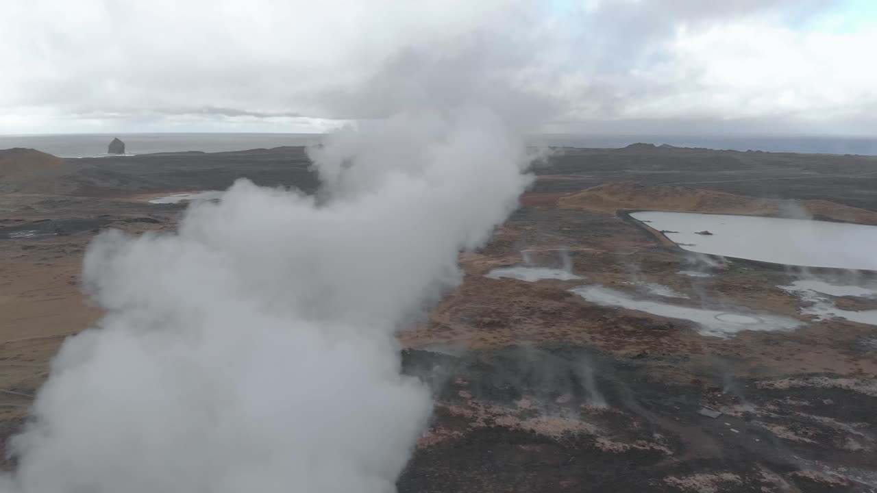 toma panorámica aérea de una fuente termal geotérmica que emana vapor del suelo
