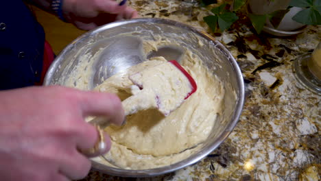 a woman folds in whipped egg whites into dough - close up